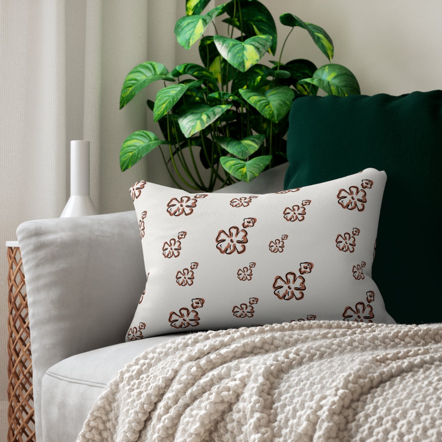 Decorative pillow with floral pattern on a couch with a plant in the background