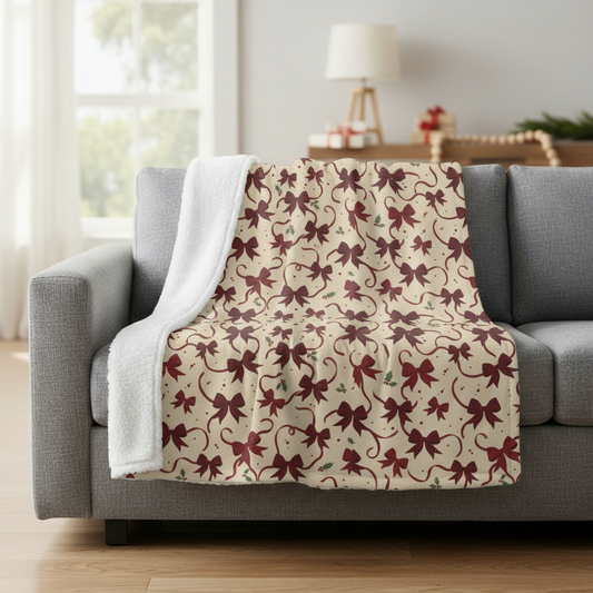 Decorative blanket with bow pattern draped over a gray sofa in a living room.