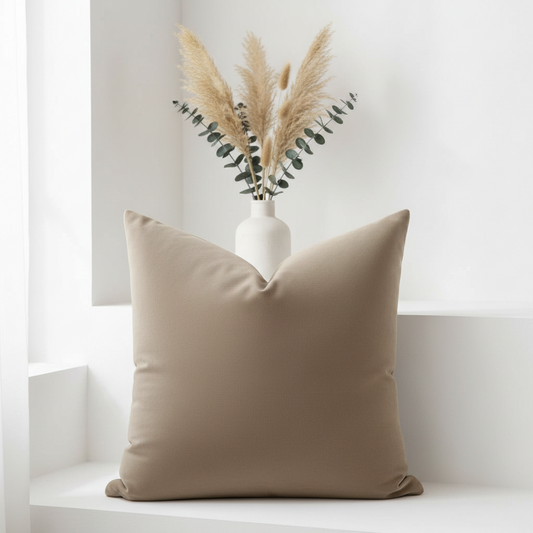 Warm taupe throw pillow 26x26 with relaxed fill styled with dried pampas grass on white surface - neutral home decor