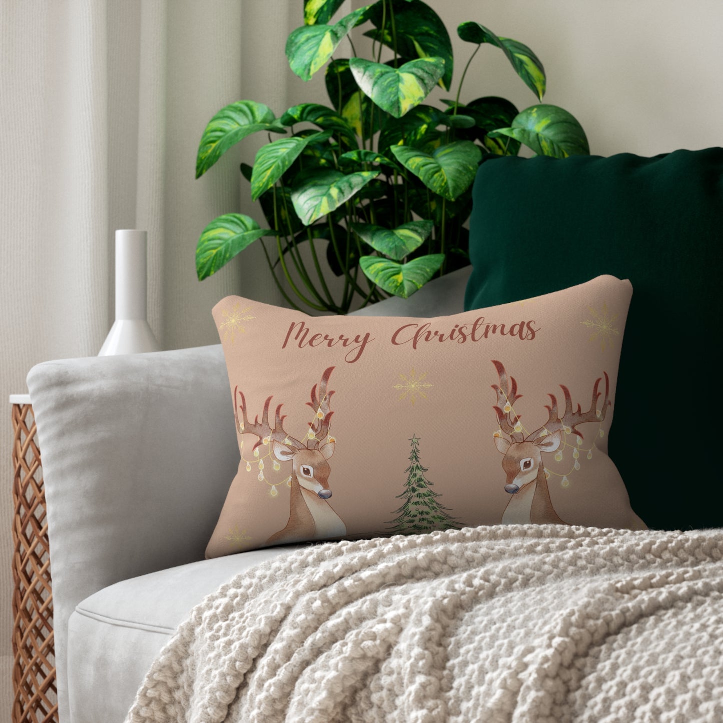 Decorative pillow with reindeer and Christmas tree design on a couch with a plant in the background
